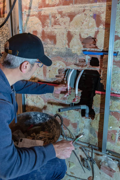istock Professional plumber installing a water pipe system inside an exposed brick wall in the middle of a work 2061101881