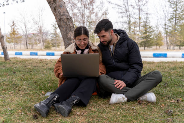 istock Students using laptop in university garden. University students studying on the lawn at the university. 2061102411