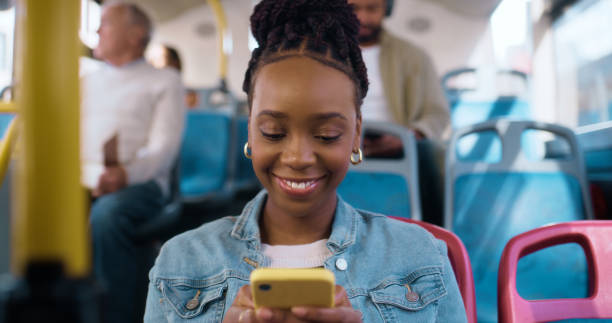 istock Woman, bus and happy with phone for texting, reading and comic meme for post on web in public for travel. African girl, transport and smile with smartphone, social media or mobile application in city 2061104510