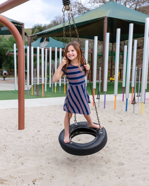 istock Young girl playing on spinning tire in a park 2061152650