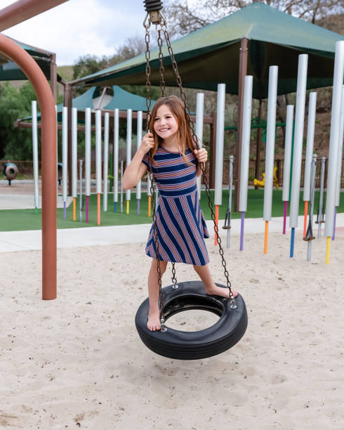 young girl playing on spinning tire in a park - freedom tire swing tire swing imagens e fotografias de stock
