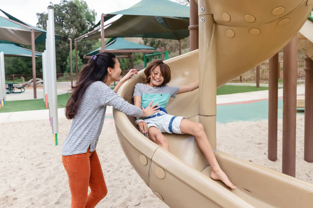 istock Mother and son playing on a slide at a park 2061153164
