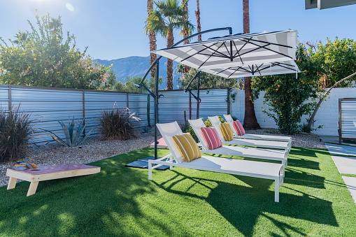 Backyard chaise lounge chairs outdoors with umbrellas and sunshine in Palm Springs, California