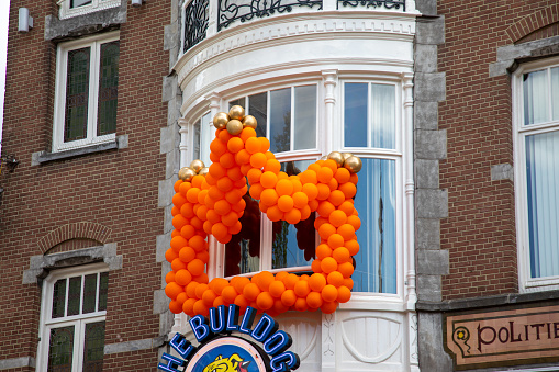 Amsterdam, Netherlands - April 26, 2022: Get into the festive spirit of King's Day in Amsterdam with this vibrant background photo featuring a multitude of orange balloons or balls texture decorating the city streets. Capture the essence of this Dutch national holiday with the colorful and lively atmosphere depicted in this image.