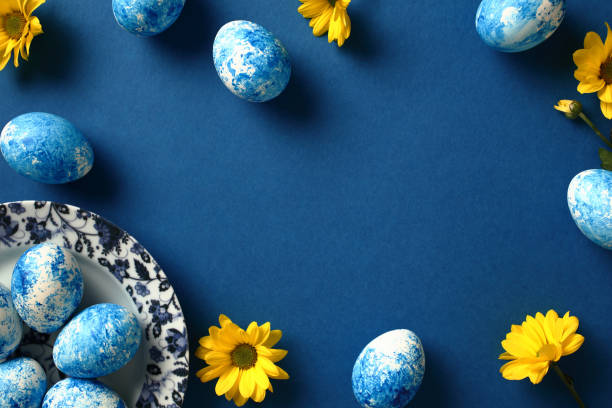 istock Happy Easter greeting card. Easter eggs on plate and yellow flowers on dark blue background. 2061240032