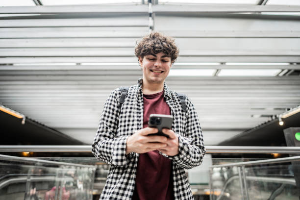 Young transgender male using mobile phone at subway station