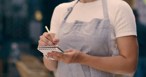 istock Hands, waiter and writing order in restaurant for service, hospitality and taking notes in coffee shop. Barista, person and server with closeup of notebook for menu and helping with apron in a cafe 2061261654