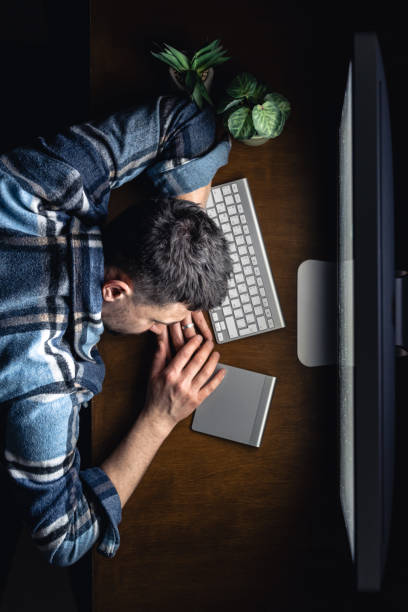 istock A man sleeps, lying in front of a computer on his desktop at night, top view. 2061284631