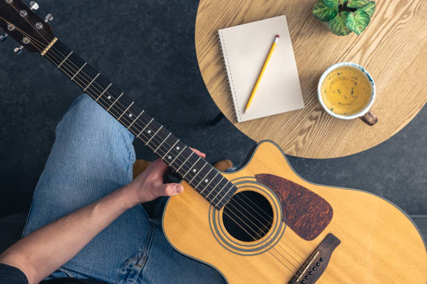 istock A man with an acoustic guitar and a notepad with a cup on the table, top view. 2061294997