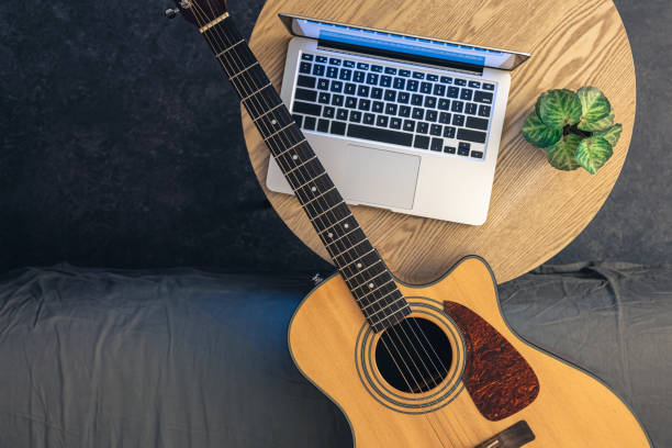 istock Acoustic guitar and laptop on a wooden table, top view. 2061295103