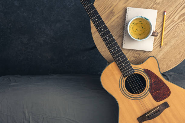 istock Musical background with acoustic guitar, notepad and cup of tea on the table. 2061295127