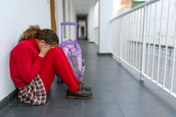 istock Girl in school uniform with backpack alone crying sitting in the school corridor. 2061297215