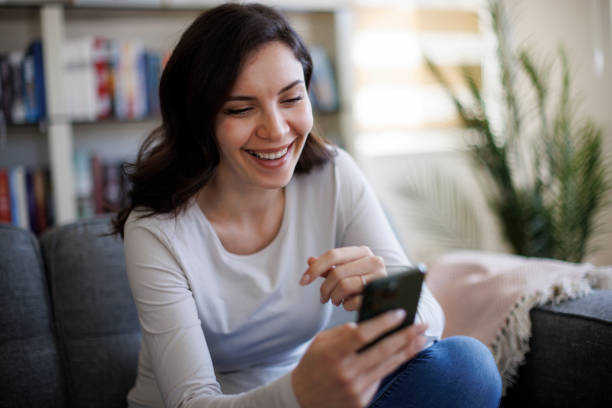 istock Young smiling woman using smart phone at home 2061444779