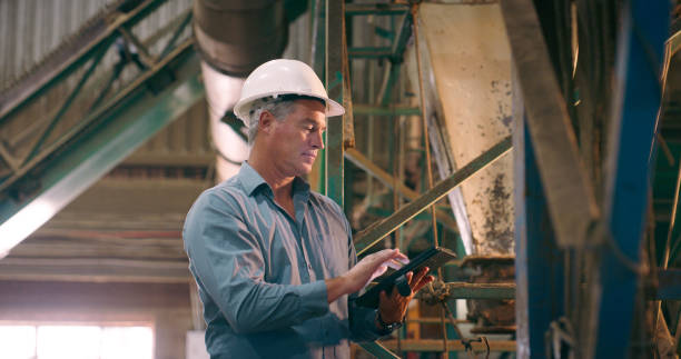 istock Tablet, helmet and mature man with engineering, industrial and inspection with online software or internet. Typing architect and employee with tech or digital app with construction safety or hard hat 2061481023