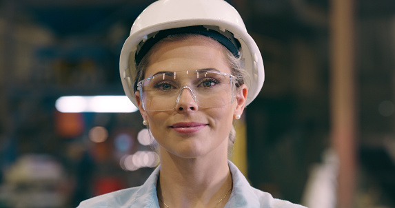 Woman, portrait and safety goggles with engineer in workshop, construction or maintenance. Manufacturing, production and engineering with glasses for protection, factory with labor and helmet
