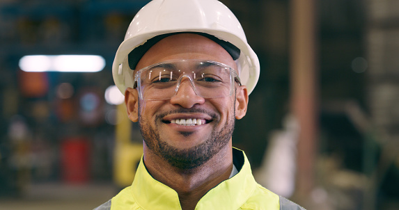 Man, portrait and safety goggles for engineer in workshop, construction or maintenance with smile. Manufacturing, production and engineering with glasses for protection, factory with labor and helmet