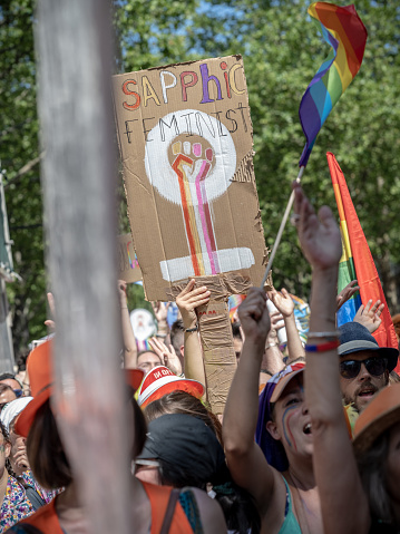 Paris, France - June 24, 2023: A poster in English at the 2023 Paris gay pride lifted above a crowd on which in is written 'sapphic feminist'