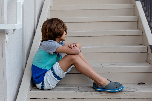 Young boy sitting sad on stairs