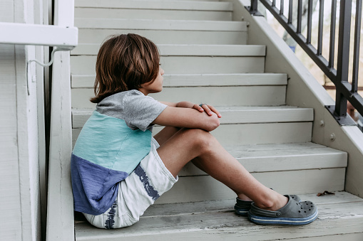 Young boy sitting sad on stairs