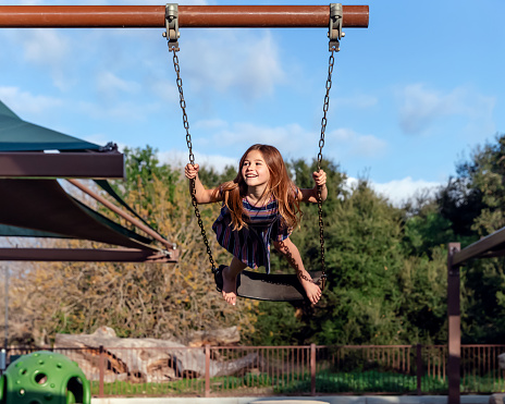 Young girl standing on swing