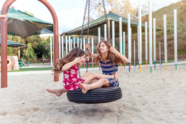 istock Sisters playing on spinning tire at a park 2061527723