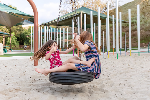 Sisters playing on spinning tire at a park