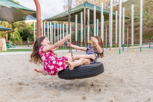 Sisters playing on spinning tire at a park