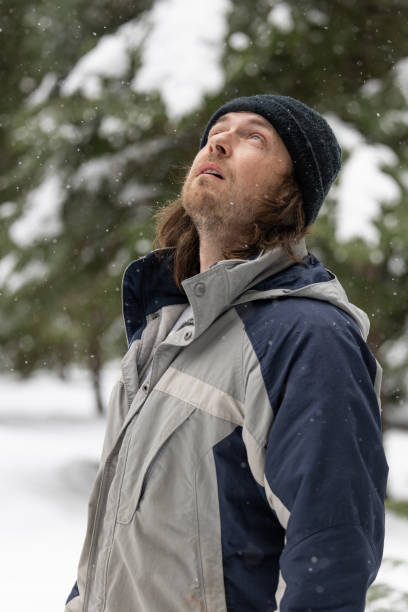 istock A man wearing a blue and gray jacket and a black hat is looking up at the sky 2061565182