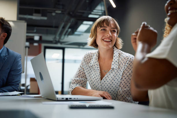 Three happy multiracial business people in businesswear smiling during discussion at meeting in office Three happy multiracial business people wearing businesswear smiling during discussion at meeting in office professional woman smiling stock pictures, royalty-free photos & images