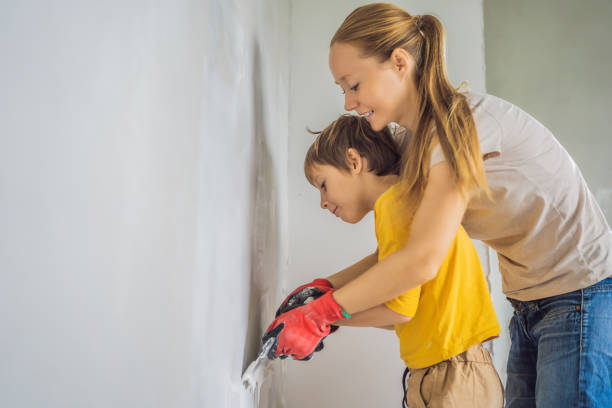 woman with hir son makes repairs at home, she teaches boy to plaster the walls with a spatula in his hands - plaster plasterer work tool child imagens e fotografias de stock