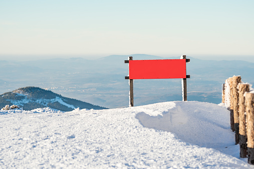 Sudetes, a red board on the top of the mountain, a winter mountain landscape, a view from the top of Mount Snieznik onto a vast valley.