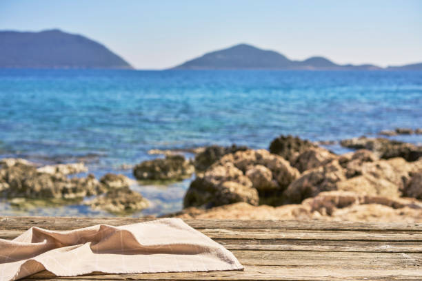 Empty wooden table with tablecloth over summertime seaside background