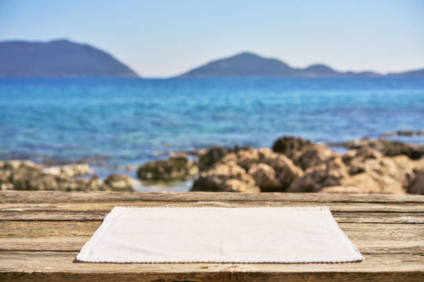 Empty wooden table with tablecloth over summertime seaside background