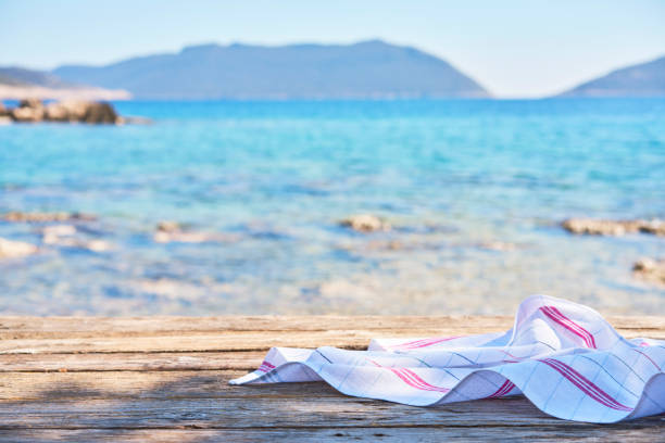 Empty wooden table with tablecloth over summertime seaside background