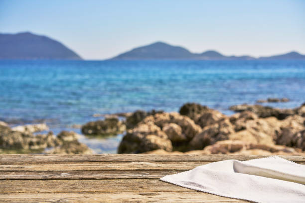 Empty wooden table with tablecloth over summertime seaside background