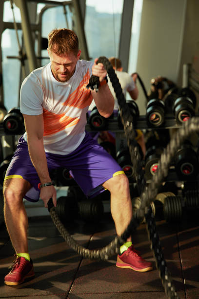 istock Athletic young man with battle rope doing exercise in functional training fitness gym 2061708441