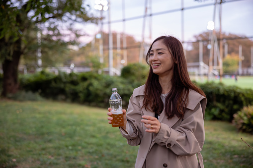 Woman holding a bottle of tea in public park