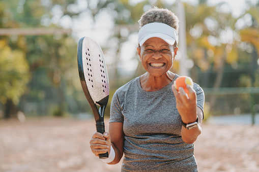 Senior woman holding beach tennis racket and ball