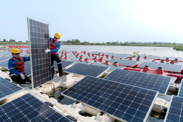 istock Male workers repair Floating solar panels on water lake. Engineers construct on site Floating solar panels at sun light. clean energy for future living. Industrial Renewable energy of green power. 2061756856
