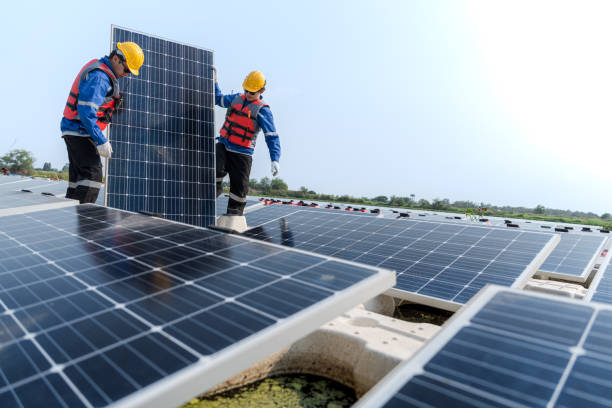 istock Male workers repair Floating solar panels on water lake. Engineers construct on site Floating solar panels at sun light. clean energy for future living. Industrial Renewable energy of green power. 2061757369
