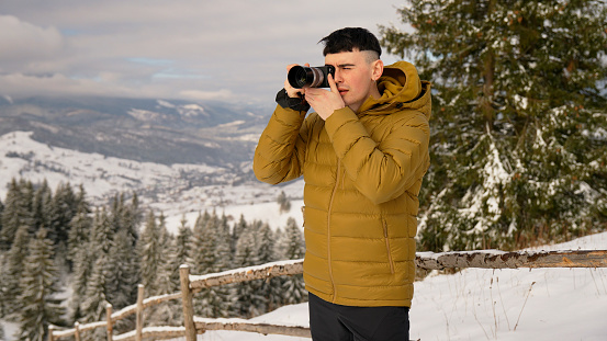 Young man takes photos in winter landscape