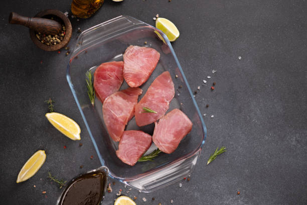 stücke von frischem thunfisch fischfilet in glaskochform und sojasaucen-marinade in einem soßenschiffchen - raw tuna steak marinated sauces stock-fotos und bilder