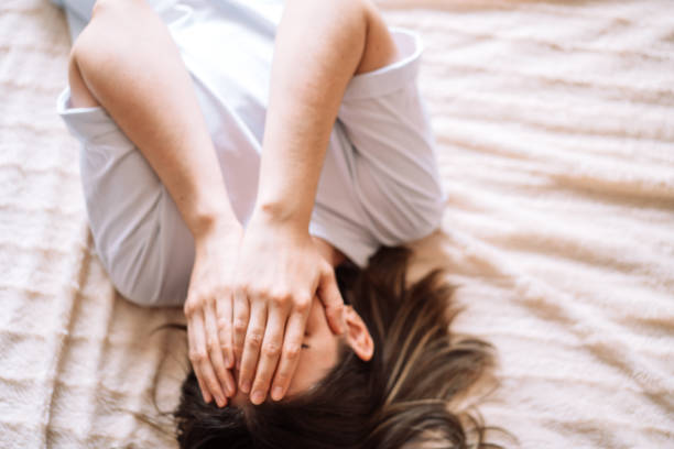 istock Lady covered her face with her hands while lying on the bed 2061807880
