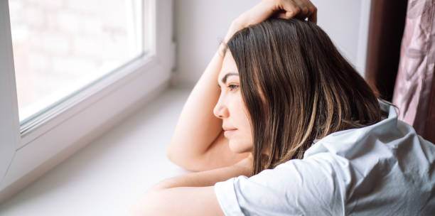 istock Sad lady lay down on the windowsill and looks out the window 2061807881
