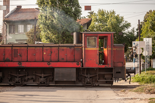 Picture of a kleinlokomotive, an old red lovomotive, getting ready to shunt wagons of a freight train in Smederevo, Serbia.