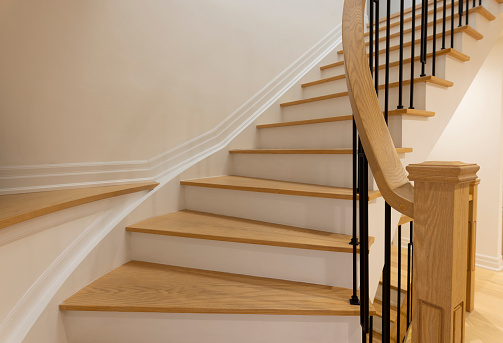 Staircase custom built home interior with wood staircase and white walls. Copy space background