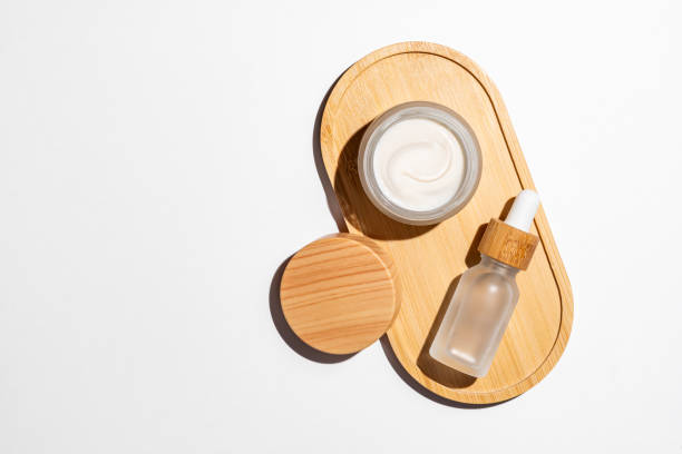 istock Natural cosmetics in white glass packaging on bamboo tray on white background. Open cream jar and dropper bottle with serum. SPA organic beauty products set. Skin care concept. 2061889912