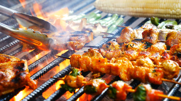 BBQ Barbecue grilled meat stick on fire flame with hot charcoal cooking outside. Beef grilling picnic outdoor with smoke bacon spicy sausage for party. Grill pork bbq on fire flame