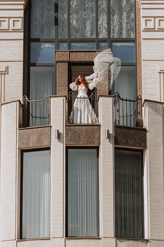 bride with a veil on the hotel balcony in a wedding dress, copy space, free space