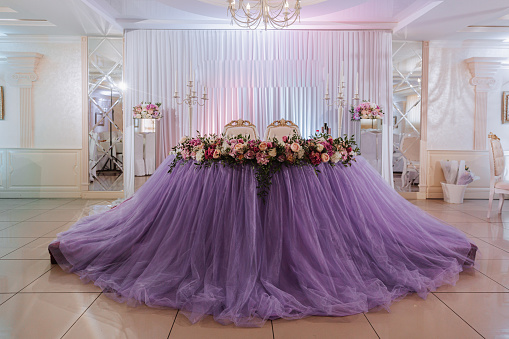 the bride's table is decorated in the restaurant in purple color, preparation for the wedding celebration.